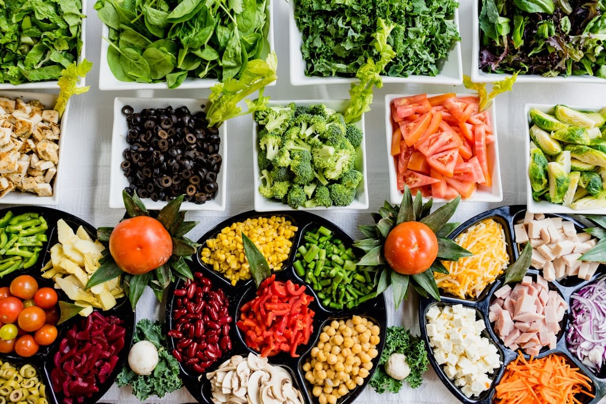Buffet de légumes frais et variés vu de dessus, évoquant une alimentation saine à la cantine